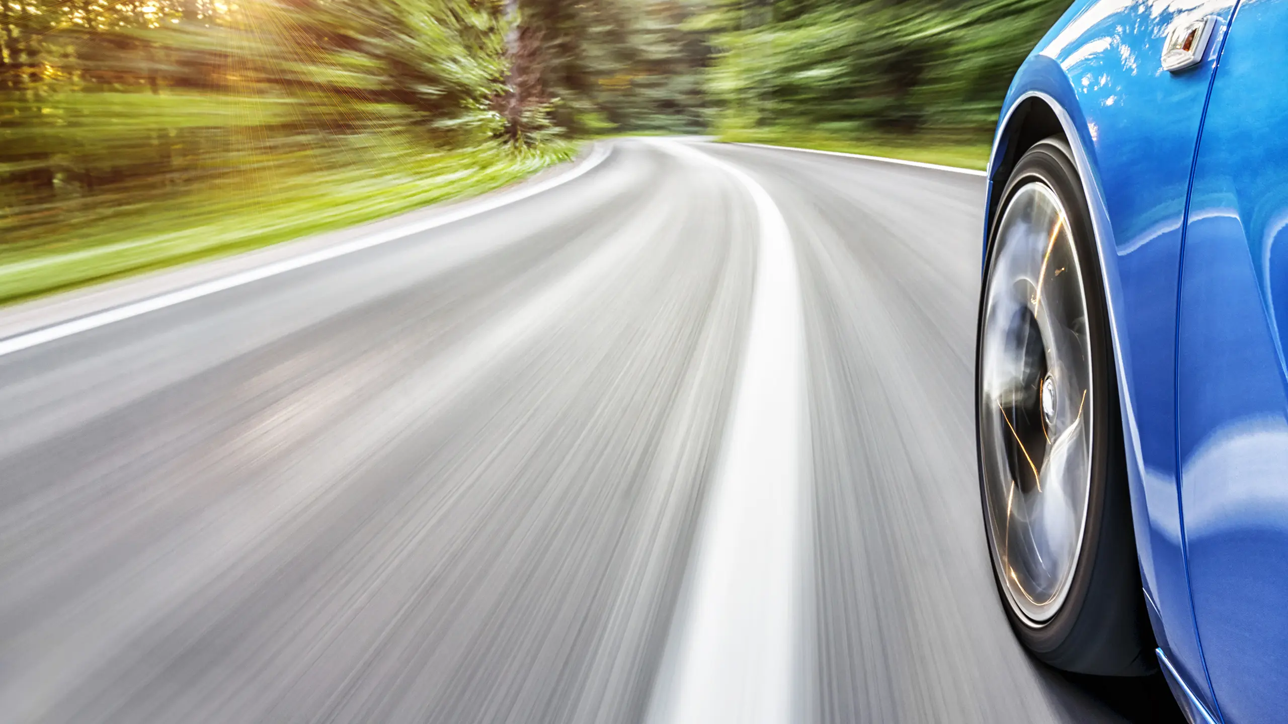 Blue car driving down highway.