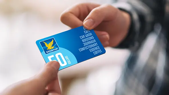 Mains tenant une carte-cadeau Ultramar.